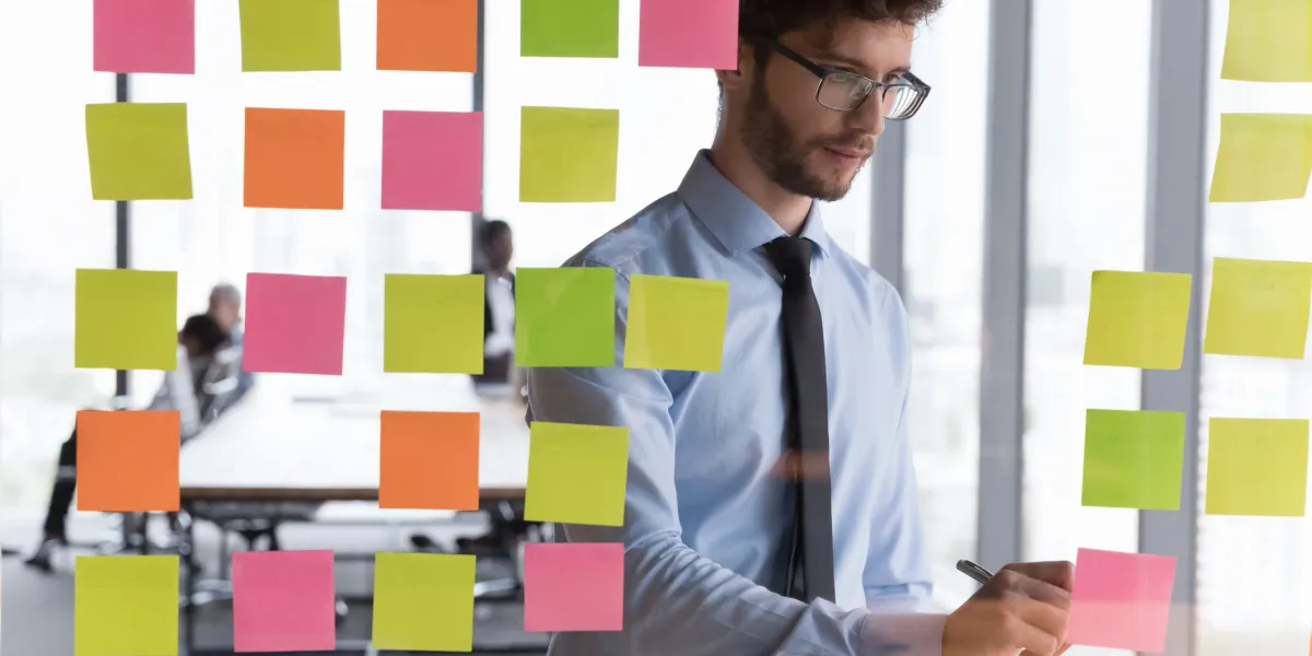 Consultant mapping out business goals on a glass wall of sticky notes